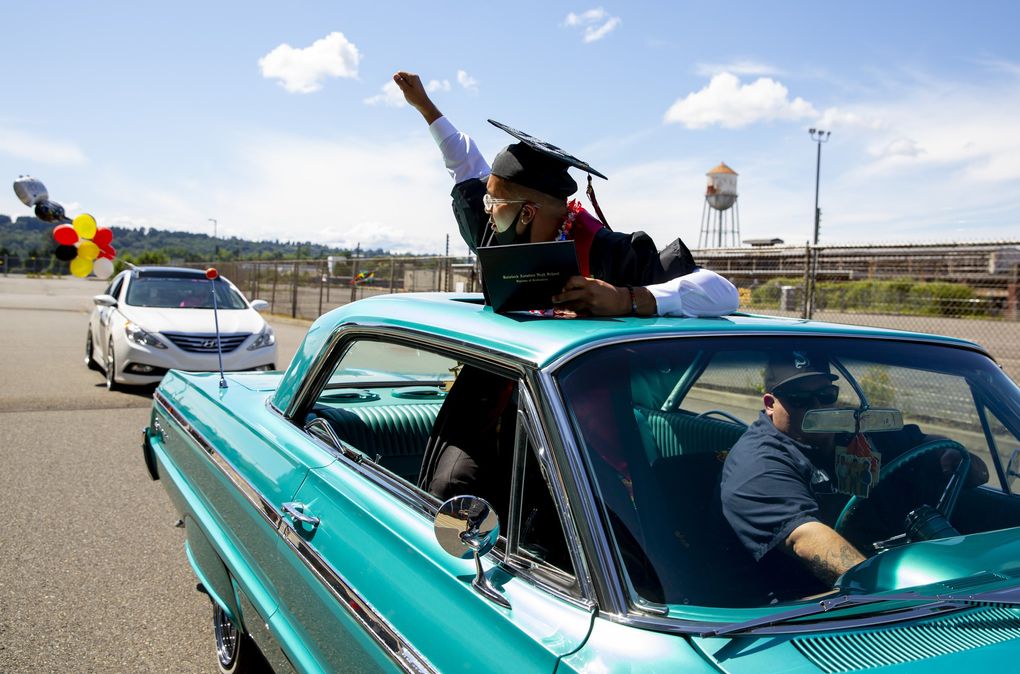 Cousin Stephen Cheadle, with Eazy Duz It Car Club, right, drives graduate Rafael Urrea in a 1964 Chevy Impala through Raisbeck Aviation High School’s drive-thru ceremonies on Thursday, June 11, 2020. (Erika Schultz / The Seattle Times)