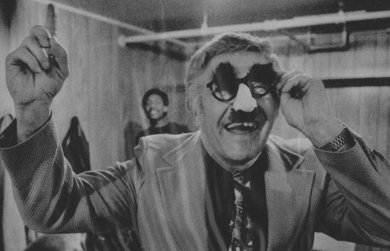 1976 Marv Harshman wearing Groucho Marx glasses in the locker room after a victory over the Oregon Ducks. Harshman and five Husky players wore Groucho Marx glasses to mock the Oregon players during pregame warmups.
Previous File Name: 1976marvpic03.jpg