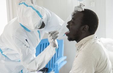 In this photo taken Sunday, June 21, 2020, an infectious disease specialist, left, takes a sample from Dr. Reagan Taban Augustino, right, now a coronavirus patient himself under quarantine, at the Dr John Garang Infectious Diseases Unit in Juba, South Sudan. The United Nations says the country’s outbreak is growing rapidly, with nearly 1,900 cases, including more than 50 health workers infected, and at the only laboratory in the country that tests for the virus a team of 16 works up to 16-hour days slogging through a backlog of more than 5,000 tests. (AP Photo/Charles Atiki Lomodong) NAI104 NAI104