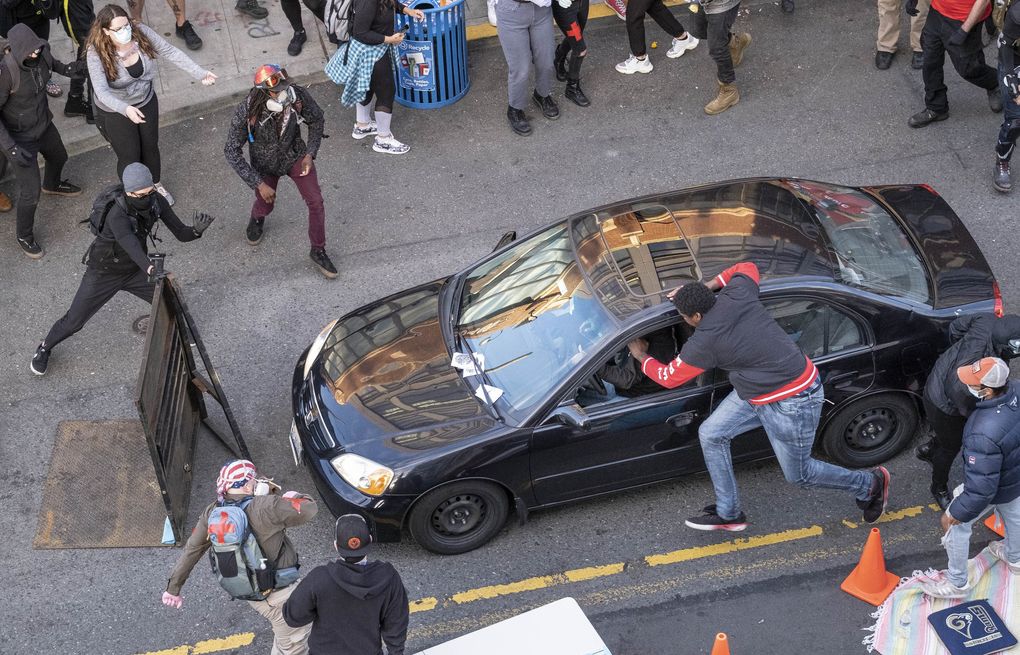 A man drives toward the crowd at 11th and Pine, injuring at least one person, before exiting the car and brandishing a firearm. The man reaching into the car to stop it was shot. Seattle saw protests sparked by the death of George Floyd move into a second week Sunday, June 7. (Dean Rutz / The Seattle Times)