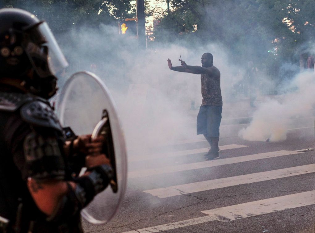 FILE – In this May 31, 2020, file photo, a protester tries to talk the police back amid tear gas in downtown Atlanta, as protests continue across the country over the death of George Floyd, a black man who died after being restrained by Minneapolis police officers on May 25. Police deployment of tear gas, pepper spray and chemical agents on protesters has raised concern that the practice may have increased the spread of the coronavirus. (Ben Gray/Atlanta Journal-Constitution via AP, File)