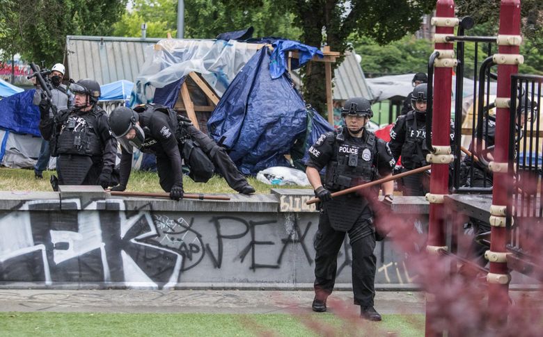 Seattle police walk across Cal Anderson Park on Wednesday morning as they clear CHOP of protesters. (Steve Ringman / The Seattle Times)