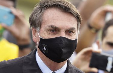 FILE – In this May 25, 2020, file photo, Brazil’s President Jair Bolsonaro, wearing a face mask amid the coronavirus pandemic, stands among supporters as he leaves his official residence of Alvorada palace in Brasilia, Brazil. Bolsonaro said Tuesday, July 7, he tested positive for COVID-19 after months of downplaying the virus’s severity while deaths mounted rapidly inside the country. (AP Photo/Eraldo Peres, File) ERA501 ERA501