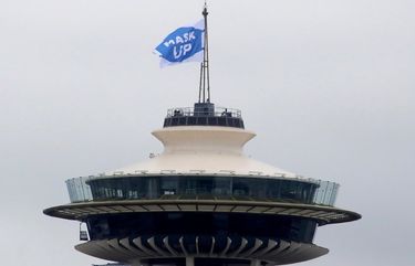 Early Friday morning, standing at the top of the Space Needle, King County Executive Dow Constantine hoists a flag that reads “Mask Up.” Wearing a mask or face covering, shown to be effective in slowing the spread of COVID-19, is also a rule statewide.
July 10, 2020
