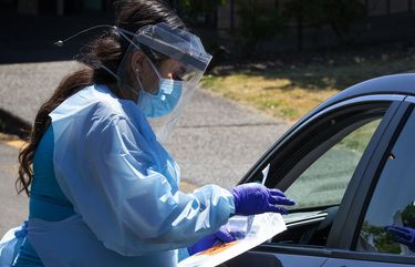 Brenda Medero, a medical assistant supervisor, gets ready to administer a  COVID-19 test to a driver at Sea Mar Community Health Center, located at 31405 18th Ave. S. in Federal Way, on July 28, 2020. The testing site, where both walk-in and drive-thru testing happens, is open on Tuesdays and Thursdays from noon to 4 p.m. For an appointment, call 253-681-6600. (Ellen M. Banner / The Seattle Times)