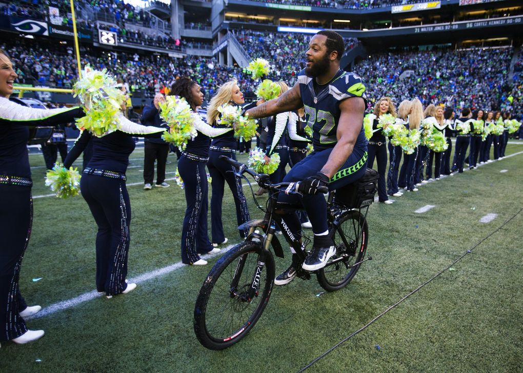 Seahawks defensive lineman Michael Bennett rides a police bike and offers high fives after Seattle defeated the Green Bay Packers in overtime to win the NFC championship at CenturyLink Field in 2015. (Dean Rutz / The Seattle Times)