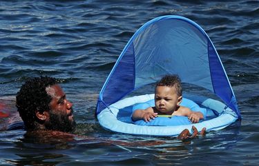 Jamel Adams cools down with 9-month-old son Jamarri during a Sunday that hit the mid-80s at Lake Union Park, July 26, 2020 in Seattle. 214574
