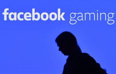 A man watches his phone at the facebook gaming stand at the Gamescom in Cologne, Germany, Tuesday, Aug. 20, 2019. Hundreds of thousands will check out the latest video games this week at the biggest event in the gaming industry. (AP Photo/Martin Meissner) MME106