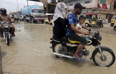Motorcyclists drive through a road  flooded by heavy rainfall in Karachi, Pakistan, Sunday, Aug. 9, 2020. Three days of heavy monsoon rains triggering flash floods killed at least dozens people in various parts of Pakistan, as troops with boats rushed to a flood-affected district in the country’s southern Sindh province Sunday to evacuate people to safer places. (AP Photo/Fareed Khan) ISL102 ISL102