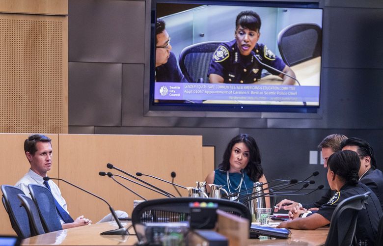 In July 2018, Then-Seattle City Councilmember Rob Johnson, left and City Councilmember M. Lorena González, center, who were both members of the council’s public-safety committee, listen to then-interim police Chief Carmen Best during the first confirmation hearing for Best as permanent chief. (Steve Ringman / The Seattle Times, file)
