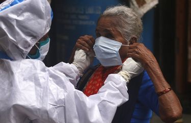 A health worker helps a woman wear a mask before screening her for COVID-19 symptoms in Dharavi, one of Asia’s biggest slums, in Mumbai, India, Tuesday, Aug. 11, 2020. India has the third-highest coronavirus caseload in the world after the United States and Brazil. (AP Photo/Rafiq Maqbool) RMX101 RMX101