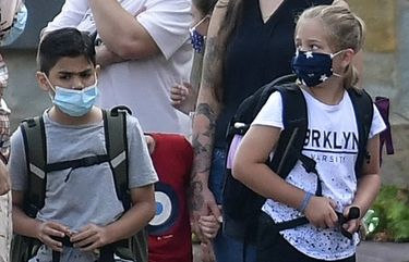 Parents wait with children on the schoolyard for the start of their first day at a school in Gelsenkirchen, Germany, Wednesday, Aug. 12, 2020. Students in North Rhine-Westphalia will have to wear face masks at all times due to the coronavirus pandemic as they return to school this Wednesday. (AP Photo/Martin Meissner) mme102 mme102