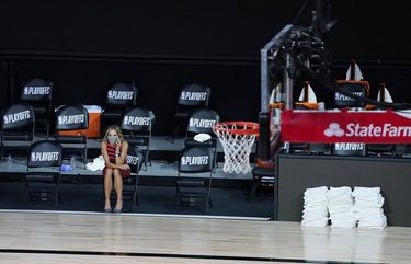 A reporter sits beside an empty court after a postponed NBA basketball first round playoff game between the Milwaukee Bucks and the Orlando Magic, Wednesday, Aug. 26, 2020, in Lake Buena Vista, Fla. The game was postponed after the Milwaukee Bucks didn’t take the floor in protest against racial injustice and the shooting of Jacob Blake, a Black man, by police in Kenosha, Wisconsin. (AP Photo/Ashley Landis, Pool) NVJL121 NVJL121