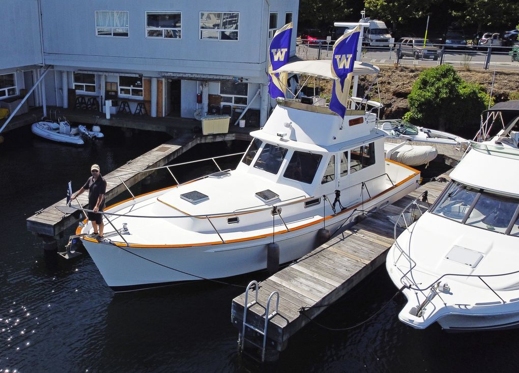 Trevor MacLachlan, the owner of Seattle Charters, flies University of Washington flags to demonstrate how he outfits his 40 foot boat “Splendido” for sailgating a Huskies football game, Tuesday, Aug. 25, 2020 on Seattle’s Lake Union. But since the pandemic, MacLachlan said he has had to return deposits for football games. MacLachlan notes he only outfits the boat with UW flags, since he graduated there in the 1990s, but will fly whatever school flag a customer brings. (Ken Lambert / The Seattle Times)