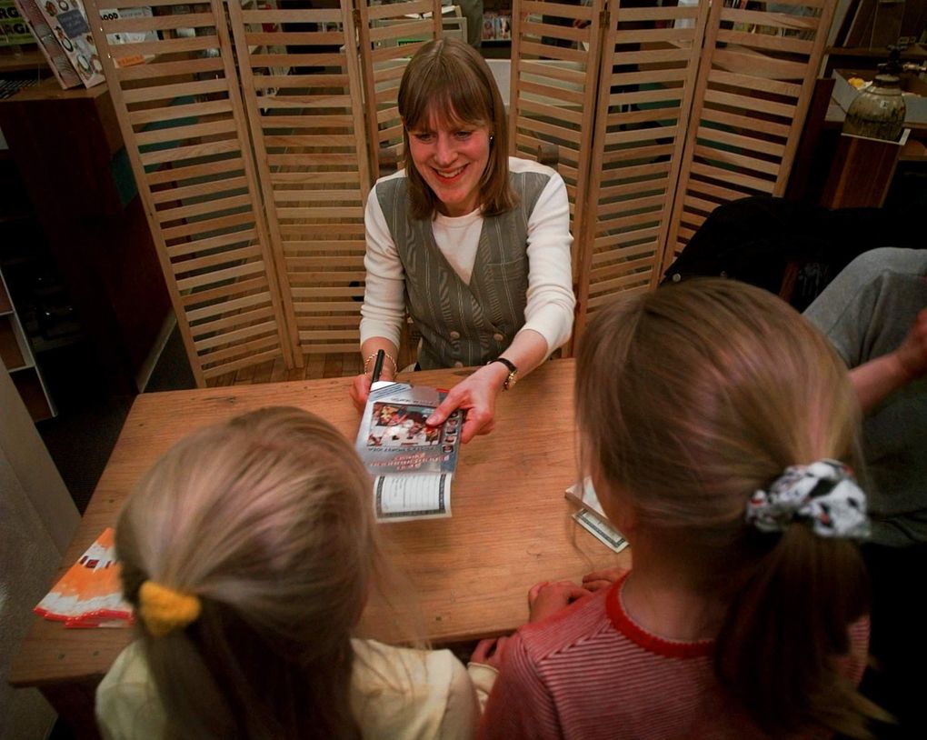 In this file photo, bestselling author Ann M. Martin signs one of her new books for Rebecca Gregg, then 7, and Taylor Schlosser, 8, during her appearance at an Albuquerque, New Mexico bookstore in April 1997. Drawing on her own experiences, Martin’s “The Baby-Sitters Club” book series was a hit with children in the 1990s, and was recently rebooted by Netflix. (AP Photo / Eric Draper)
