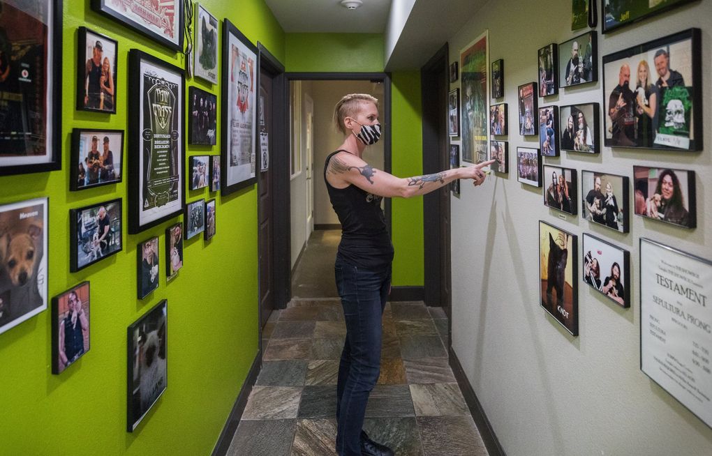 Jme Thomas points out a few of the musicians along with other performers on her walls at Motley Zoo, a “foster-based animal rescue shelter” in Redmond, Aug. 6, 2020. (Steve Ringman / The Seattle Times)