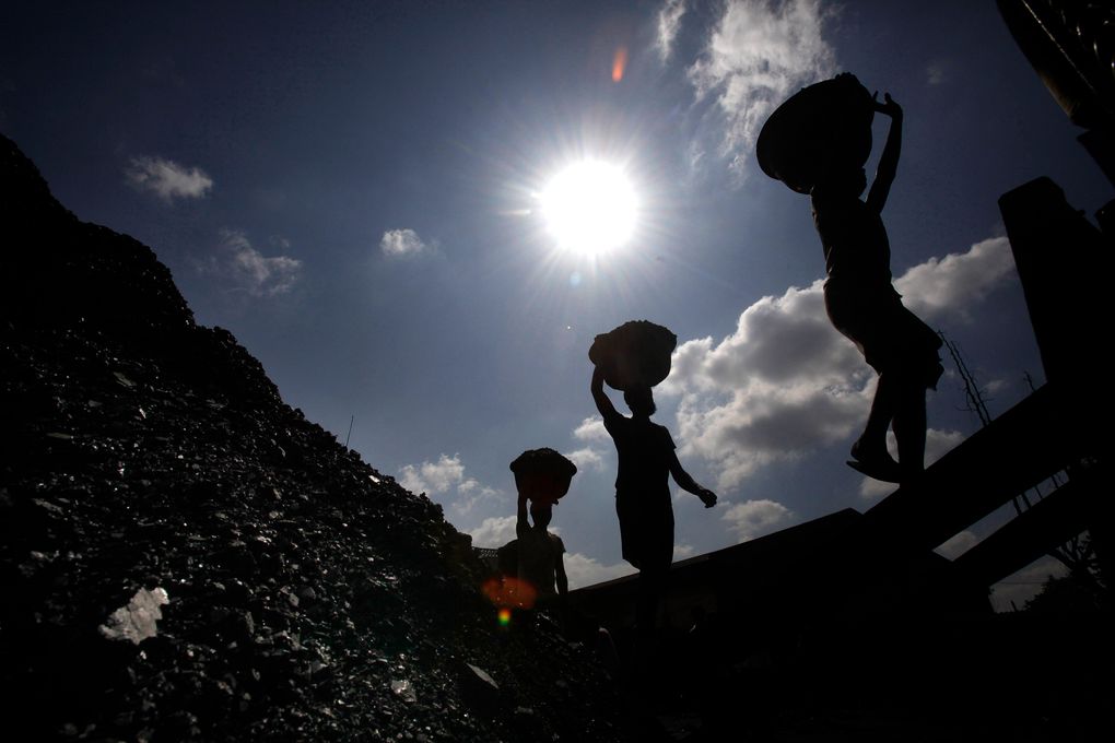FILE- In this Oct. 20, 2010 file photo, Indian laborers carry coal to load on a truck in Gauhati, India. India should commit to carbon neutrality by ending fossil fuel subsidies and investing in clean solar power as it mobilizes trillion of dollars to recover from the coronavirus pandemic, the U.N. Secretary-General António Guterres said Friday, Aug. 28, 2020. (AP Photo/Anupam Nath, File)