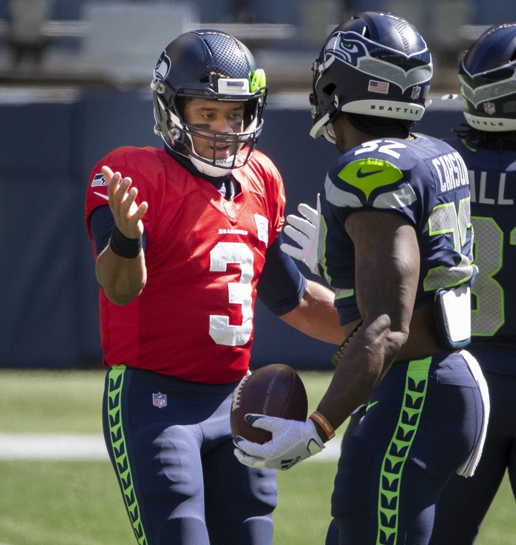 Russell Wilson welcomes running back Chris Carson on to the field for a mock game at CenturyLink Field on August 26. (Dean Rutz / The Seattle Times)