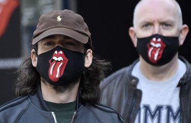 Rolling Stones fans wear face masks as they queue during the opening of Rolling Stones flagship store in London, Wednesday, Sept. 9, 2020. The shop will sell fashion and merchandise, as well as music, from the famous rock band. (AP Photo/Alberto Pezzali) FAS108 FAS108