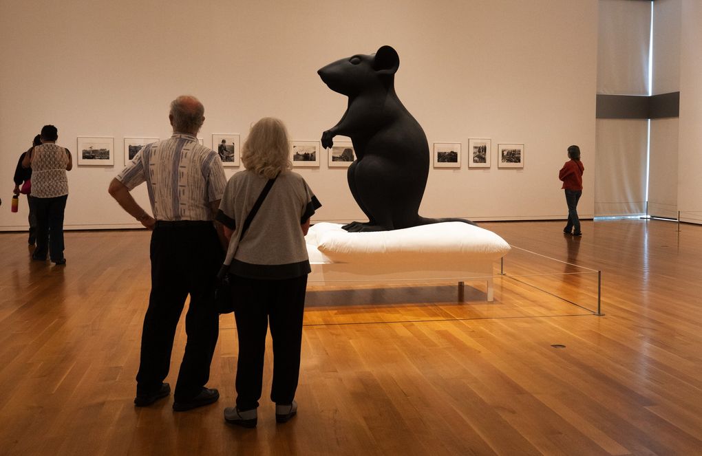 Visitors check out exhibits at the Seattle Art Museum Friday, the first day the museum reopened after pandemic closures. At center is “Mann und Maus,” of polyester resin and paint, by Katharina Fritsch. (Ellen M. Banner / The Seattle Times)