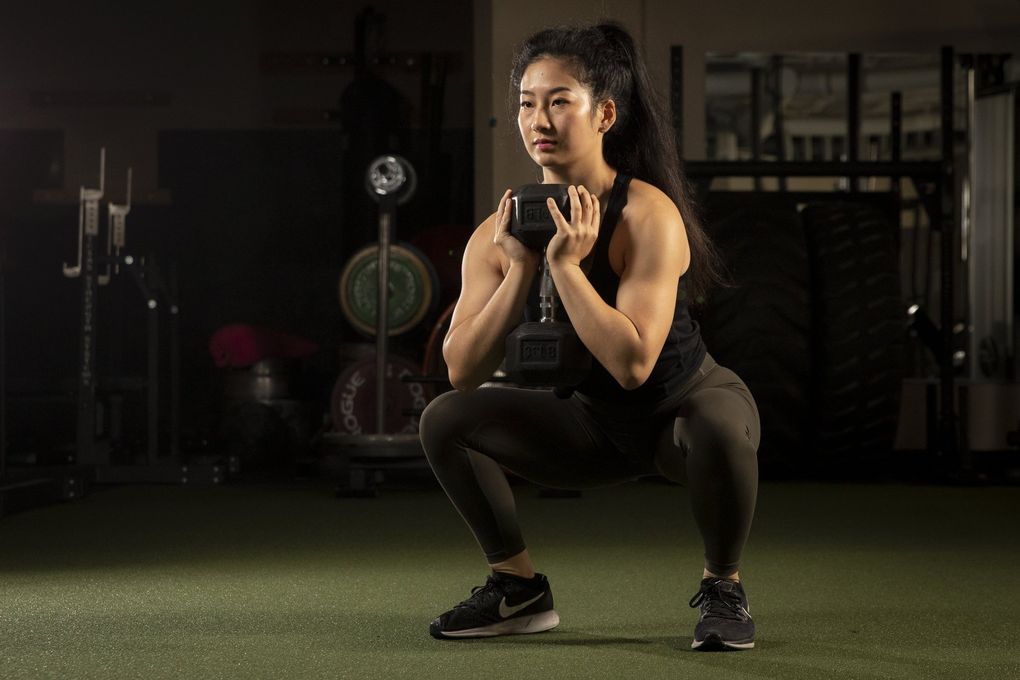 Personal trainer Laura Su demonstrates how to do use a dumbbell for weighted squats.
(Bettina Hansen / The Seattle Times)