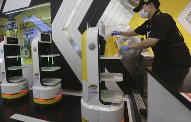 In this Sunday, Sept. 13, 2020 photo, an employee places a takeout bag with food at a robot at No Brand Burger in Seoul, South Korea. These robotic services have been seen as a selling point amid the coronavirus pandemic and its restrictions. (AP Photo/Ahn Young-joon) XSEL102 XSEL102