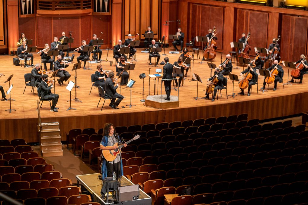 Seattle singer-songwriter Whitney Mongé performs at a distance from the Seattle Symphony musicians during the opening-night performance. (James Holt / Seattle Symphony)