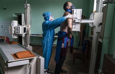 A medic wearing a special suit to protect against coronavirus prepares a patient with coronavirus for a lung X-ray at the city hospital in Stryi, Ukraine, Tuesday, Sept. 29, 2020. The worldwide death toll from the coronavirus eclipsed 1 million, nine months into a crisis that has devastated the global economy, tested world leaders’ resolve, pitted science against politics and forced multitudes to change the way they live, learn and work. (AP Photo/Evgeniy Maloletka) XSG108 XSG108