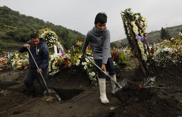 Lucas, 9, plays around helping his gravedigger dad Luciano Lopez, left, after coming to work with his father since there was no one to stay home with him to attend televised school classes, in a section of the Valle de Chalco Municipal Cemetery which opened early in the new coronavirus pandemic to accommodate the surge in deaths, on the outskirts of Mexico City, Tuesday, Sept. 22, 2020.(AP Photo/Rebecca Blackwell) RLB104 RLB104