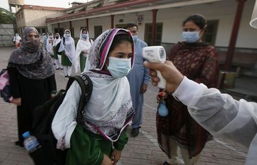 A worker checks body temperature of students upon her arrival at a school in Peshawar, Pakistan, Wednesday, Sept. 23, 2020. Pakistani officials welcomed millions of students back to middle schools following educational institutions reopened in the country amid a steady decline in coronavirus deaths and infections. (AP Photo/Muhammad Sajjad) ISL101 ISL101