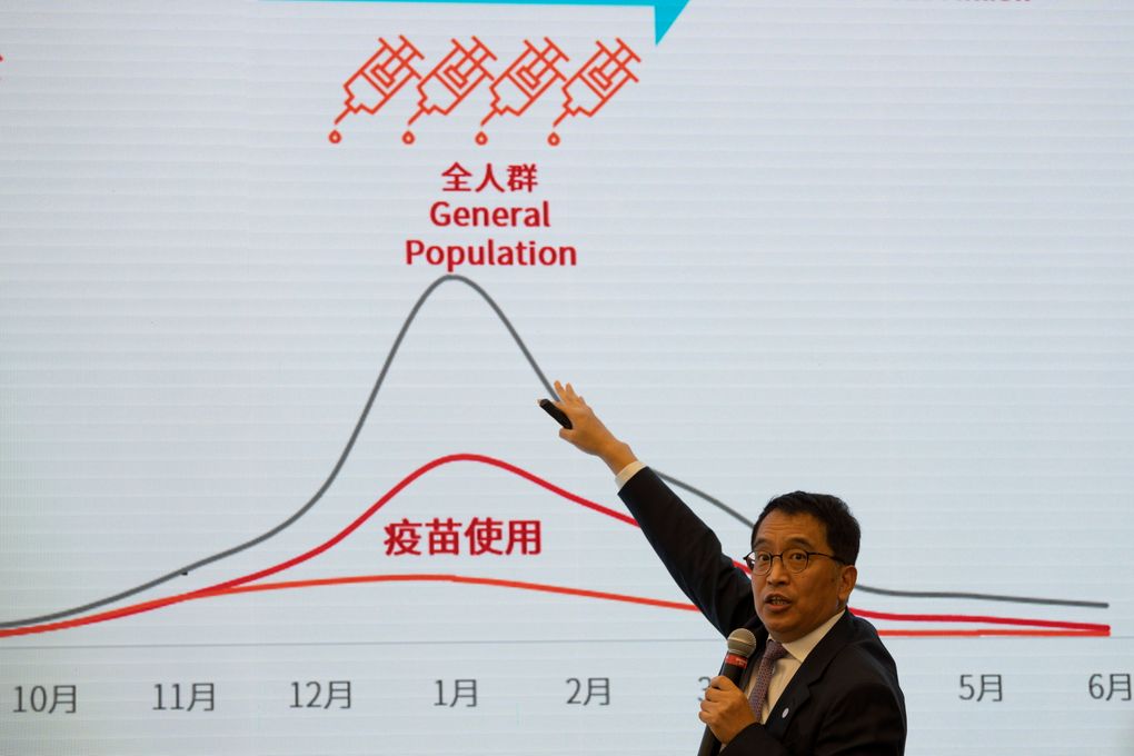 Yin Weidong, CEO of the Chinese pharmaceutical company SinoVac, points to projections of coronavirus infections and vaccinations during a tour of a vaccine factory in Beijing on Thursday. (AP Photo/Ng Han Guan)