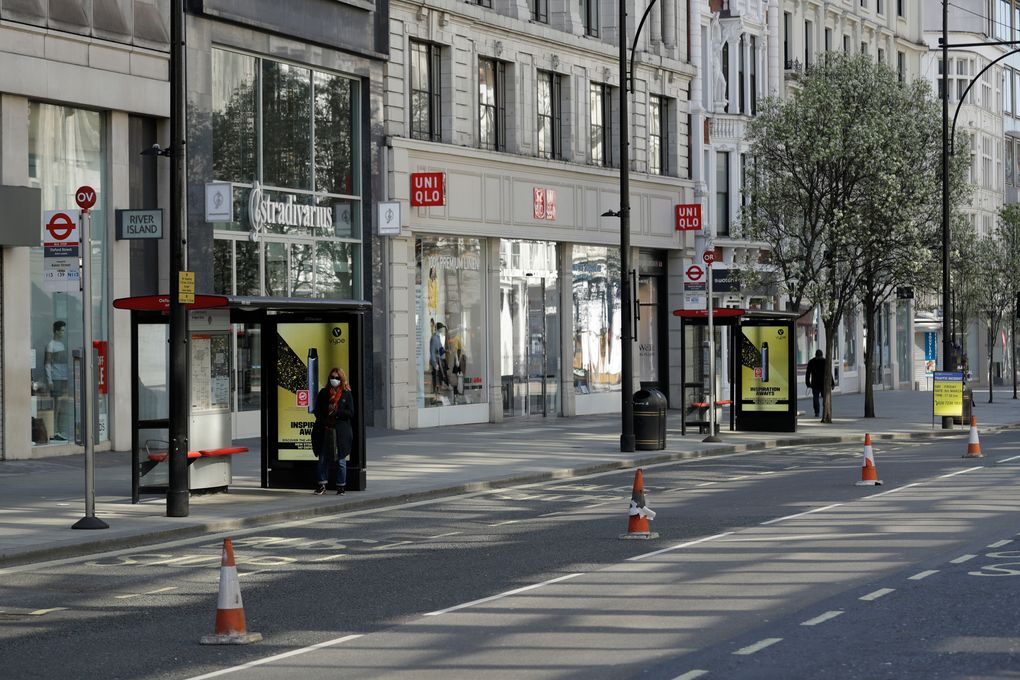 A masked woman waits at a bus stop on a deserted Oxford Street in London. Critics say Britain botched its response to the coronavirus the first time around. Now some scientists fear it’s about to do it again. The virus is on the rise again in the U.K., which has recorded almost 42,000 COVID-19 deaths, with confirmed infections at their highest level since May. (AP Photo/Matt Dunham, File)