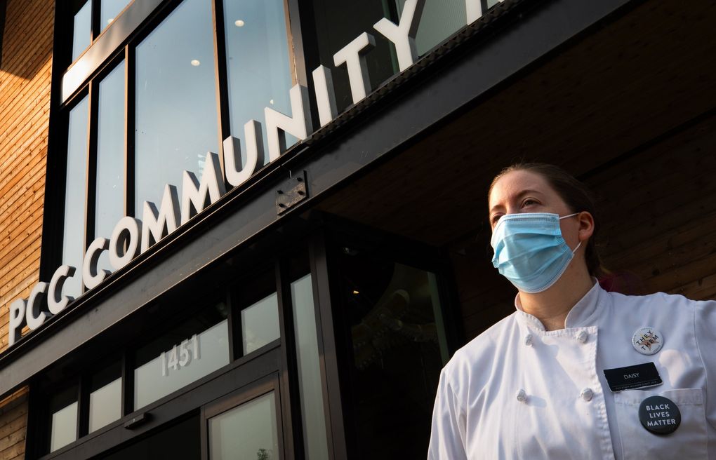 Daisy Bee, a deli helper clerk at the Ballard PCC Community Markets, stands outside the store, wearing a Black Lives Matter button, Wednesday. Swedish and Starbucks are allowing employees to wear the buttons. QFC and Bartell Drugs do not.
(Ellen M. Banner / The Seattle Times)