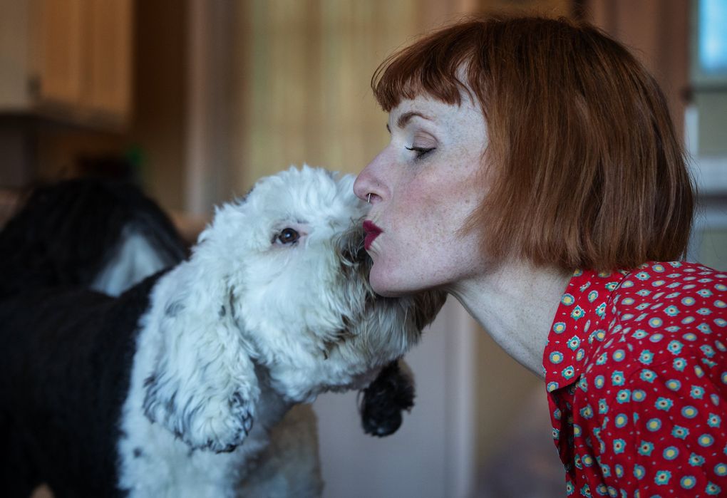 Bunny, a 14-month old Sheepadoodle, and her owner, Alexis Devine, share a kiss in their Tacoma home. Devine is teaching Bunny to communicate by pressing buttons but says they already communicate well without them. (Ellen M. Banner / The Seattle Times)