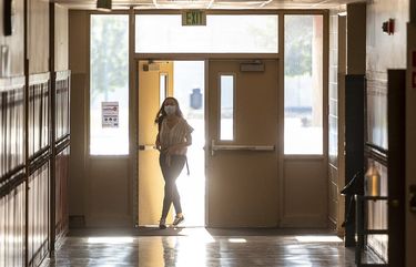 As the sunrise shines through the windows, a student walks into a quiet hallway long before the first bell rings to start class at Clarkston High School on Thursday, Aug. 27, 2020, in Clarkston, Wash.