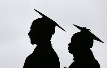 FILE – In this May 17, 2018, file photo, new college graduates line up before the start of  in East Rutherford, N.J. Many new college graduates are struggling to find work as their first student loan payments loom on the horizon. (AP Photo/Seth Wenig, File) 