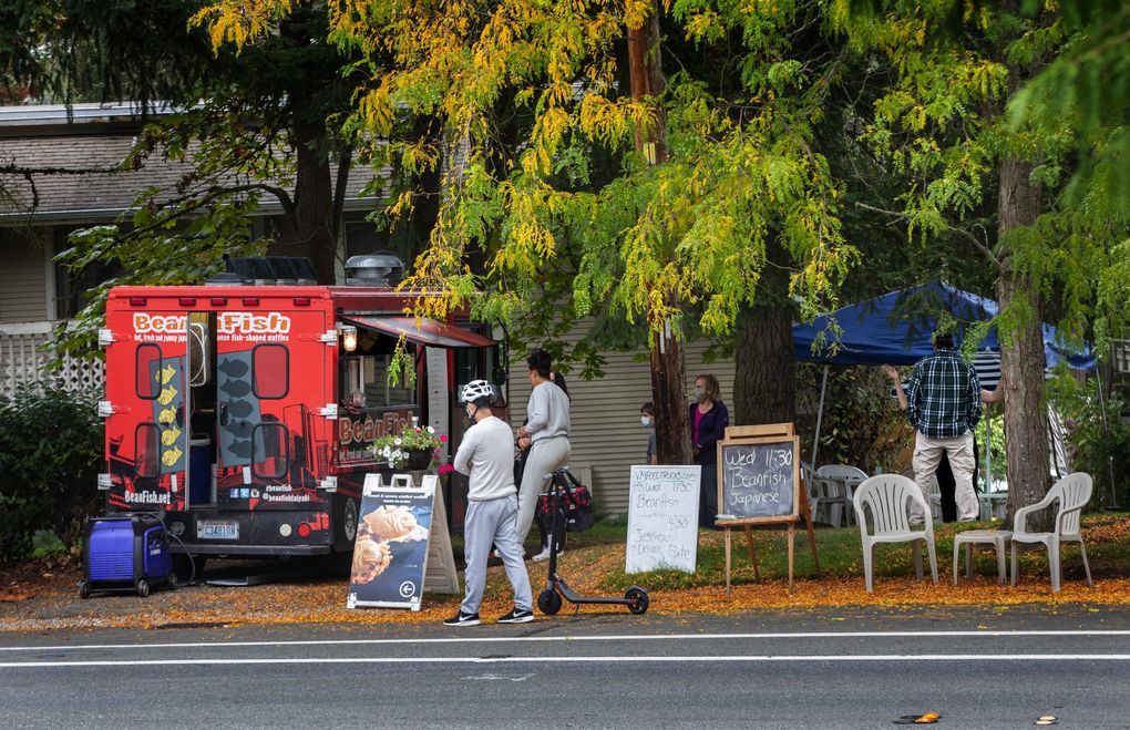 Customers line up at BeanFish, parked in a Redmond neighborhood Oct. 7, 2020. Owner Brady Woo and other food truck owners have tried different ways to survive in the pandemic. He takes his food truck to many locations all over King County seven days a week. (Ellen M. Banner / The Seattle Times)