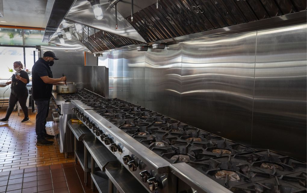 Daniel Romero, owner of the Whateke food truck, prepares sauce at Chop Kitchens to get his truck ready for the business day ahead on Thursday, Oct. 8, 2020. At left is Sandra Cruz, a chef at Whateke.
(Ellen M. Banner / The Seattle Times)