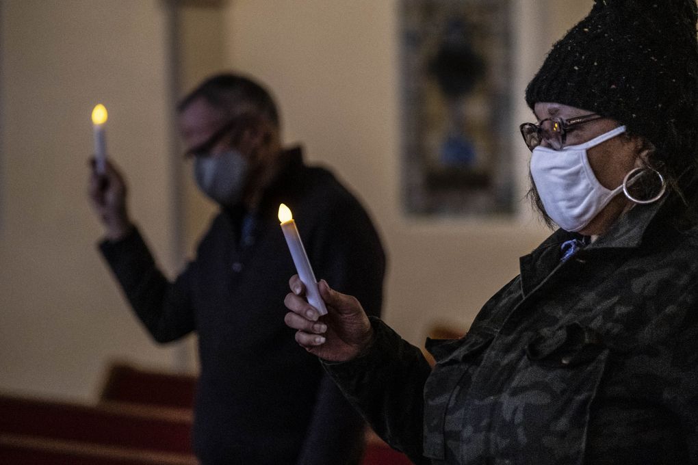 Dr. Phyllis Gearring-Anderson, right, joins parishioners at First AME Church in a candlelight vigil for victims of COVID-19 on Monday. The Rev. Carey Anderson, of First AME Church on Capitol Hill, led the candlelight vigil and service, which were also streamed online. (Dean Rutz / The Seattle Times)