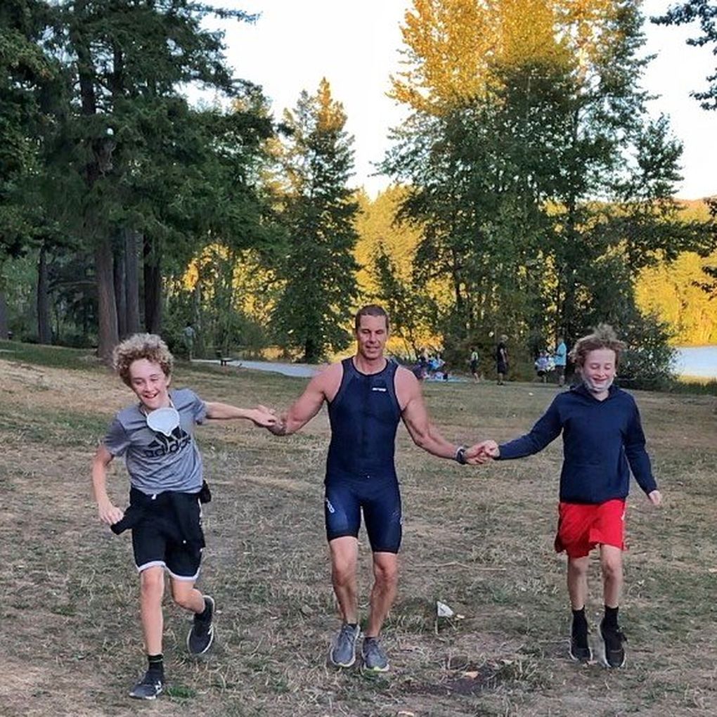 Jimmy Watts finishes his “Solo Man” triathlon at Lake Padden in Bellingham on Sept. 6 while holding hands with his sons, Taylor (left) and Cody (right). (Photo courtesy Jimmy Watts / )
