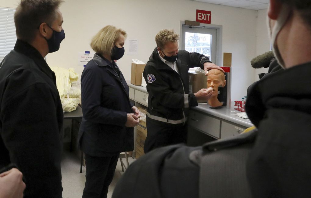 Mayor Jenny Durkan is shown Friday how a swab is used in a COVID-19 drive-up testing site on North Aurora. (Alan Berner / The Seattle Times)