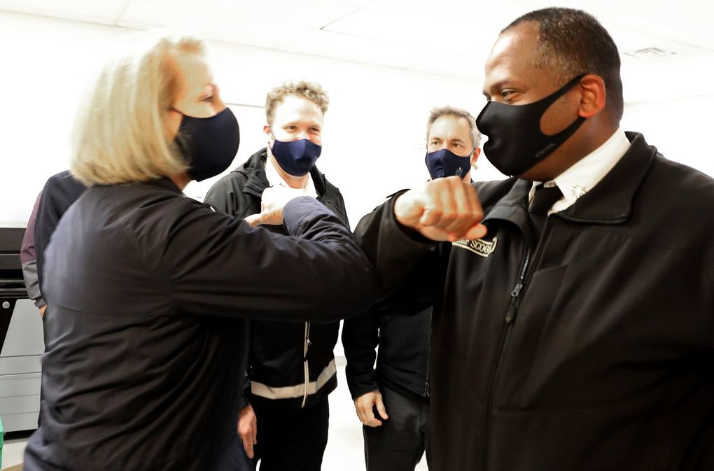 Mayor Jenny Durkan and Seattle Fire Chief Harold Scoggins elbow-bump after arriving separately at the north Seattle COVID-19 testing site on Aurora. (Alan Berner / The Seattle Times)