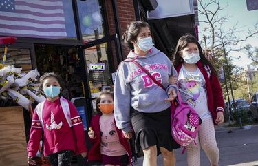 Pedestrians in masks pass a store on Thursday, Oct. 15, 2020, as government restrictions on business activity limit operations due to an increase of COVID-19 cases, in the Far Rockaway neighborhood of the borough of Queens in New York. After shutdowns swept entire nations during the first surge of the coronavirus earlier this year, some countries and U.S. states are trying more targeted measures as cases rise again around the world. (AP Photo/John Minchillo) NYJM212 NYJM212