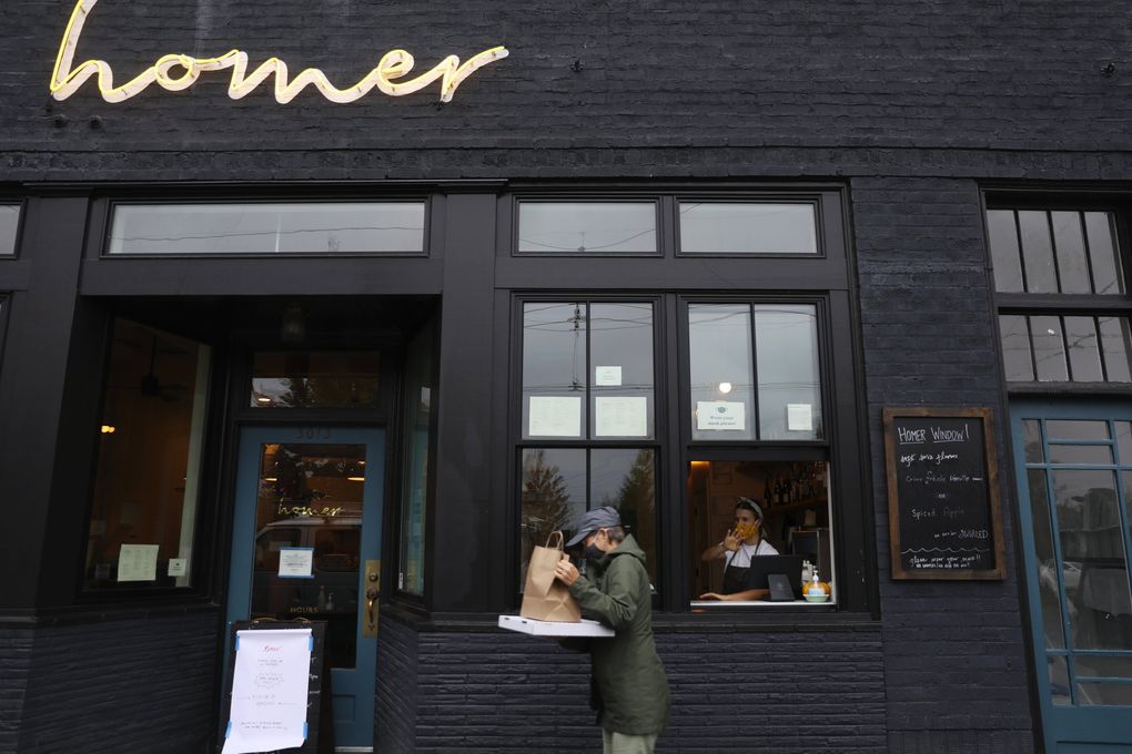 Kaylee Baker, right, of Romeo Pizza waves as a customer leaves with an order, Monday, Oct. 19, 2020, on Beacon Hill. (Ken Lambert / The Seattle Times)
