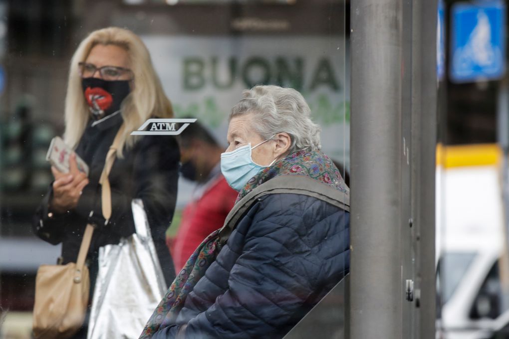 People wear face masks to prevent the spread of COVID-19 as they wait at a bus stop, in Milan, Italy, Wednesday, Oct. 14, 2020. Italian Premier Giuseppe Conte says the aim of Italy’s new anti-virus restrictions limiting nightlife and socializing is to head off another generalized lockdown. (AP Photo/Luca Bruno)