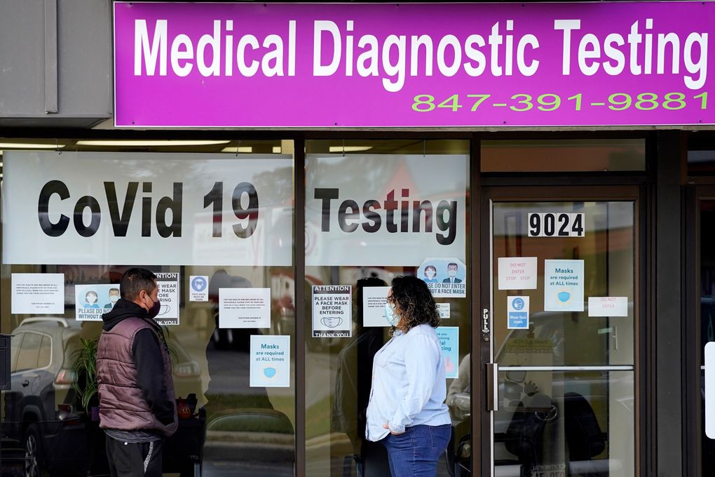 FILE – In this Oct. 21, 2020, file photo, Exam Corp Lab employee, right, wears a mask as she talks with a patient lined up for COVID-19 testing in Niles, Ill. The United States is approaching a record for the number of new daily coronavirus cases in the latest ominous sign about the disease’s grip on the nation. (AP Photo/Nam Y. Huh, File)