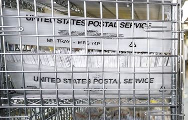 In this photo taken Wednesday, July 22, 2020 in New York, locked cages of USPS bins loaded with ballots await counting in a secured facility. (AP Photo/John Minchillo) NYJM119