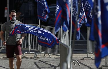 A man sets up flags as supporters of President Donald Trump protest outside the Pennsylvania Convention Center, where vote counting continues, in Philadelphia, Monday, Nov. 9, 2020, two days after the 2020 election was called for Democrat Joe Biden.  (AP Photo/Rebecca Blackwell) RLB107 RLB107