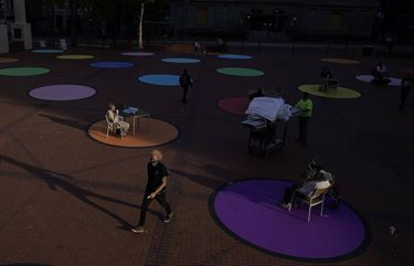 People sit on colored circles to keep social distance amid the COVID-19 pandemic Monday, Nov. 2, 2020, in Portland, Ore. (AP Photo/Marcio Jose Sanchez)