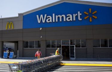 An employee wearing a protective mask pulls carts towards a Walmart store in Lakewood, California, U.S., on Thursday, July 16, 2020. Walmart Inc. will require customers to wear masks in all of its U.S. stores to protect against the coronavirus, an admission that the nation’s pandemic has reached new heights and setting up potential confrontations with customers who refuse to don them. Photographer: Patrick T. Fallon/Bloomberg 775535622